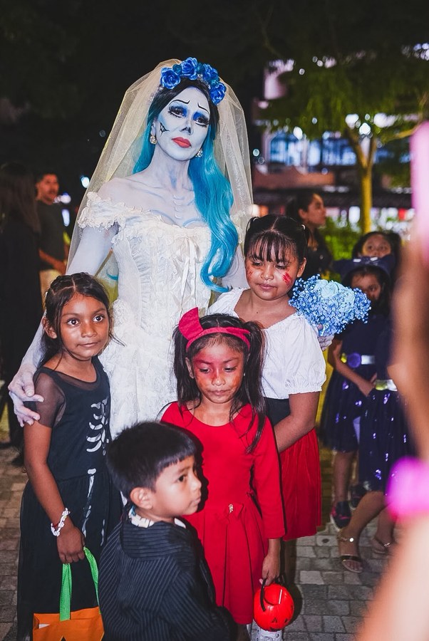 Mujer caracterizada como catrina novia con cabello azul y vestido blanco en la Callejoneada de los Monstruos 2026 en Zihuatanejo