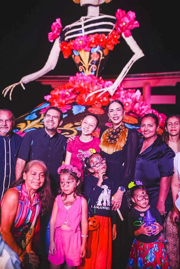 La presidenta Lizette Tapia Castro con familias y niños caracterizados de catrinas frente a la Catrina Monumental en Zihuatanejo