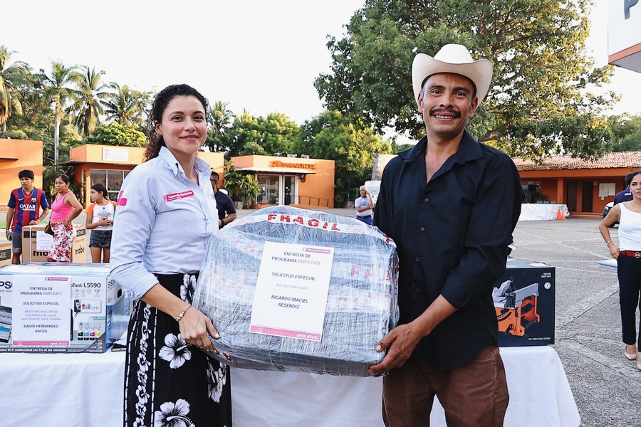 La directora de Desarrollo Económico, Evelyn Valdovinos Leyva, entrega un molino para café a un beneficiario del programa Empléate en Zihuatanejo