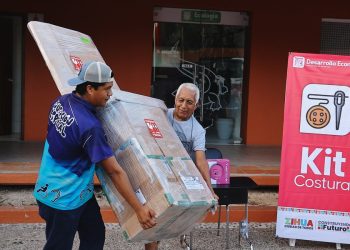 Beneficiarios cargan un kit de costura durante la última entrega anual del programa Empléate en Zihuatanejo
