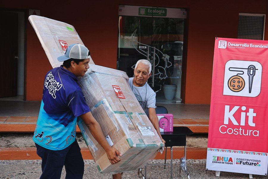 Beneficiarios cargan un kit de costura durante la última entrega anual del programa Empléate en Zihuatanejo