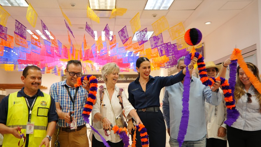 La presidenta municipal Lizette Tapia Castro recibe con papel picado a los pasajeros del primer vuelo de la temporada invernal en Zihuatanejo