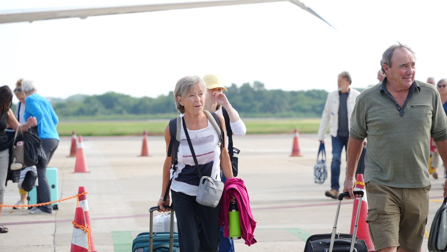 Turistas canadienses del vuelo inaugural de WestJet caminan por la pista del Aeropuerto Internacional de Zihuatanejo
