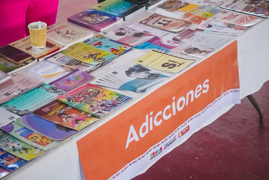 Mesa con material informativo sobre adicciones y salud mental en el encuentro juvenil de Zihuatanejo