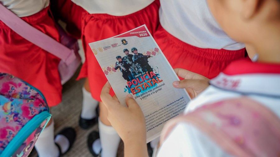 Estudiante de primaria sostiene un volante de la convocatoria Únete a la Policía Estatal durante el programa Un Día con el Policía