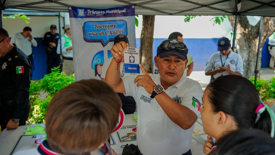 Agente de Tránsito Municipal muestra a estudiantes una tarjeta de educación vial durante el programa Un Día con el Policía en Zihuatanejo